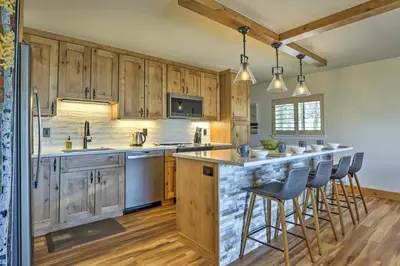 a kitchen with wooden cabinets and a counter with bar stools at MtnandLake Views and 3 Mi to Skiing Dillon Condo in Dillon