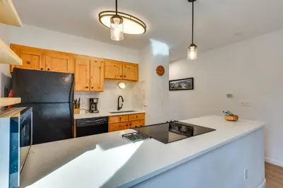 a kitchen with a black refrigerator and wooden cabinets at Walk to Winter Park Bus From Fraser Condo! in Fraser