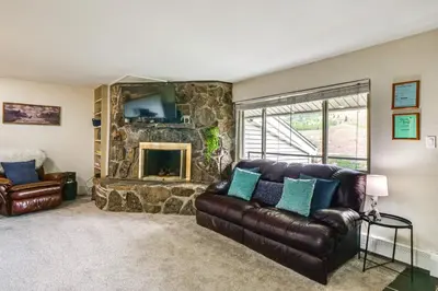 a living room with a leather couch and a stone fireplace at 6 Mi to Keystone Resort Cozy Lake Dillon Condo! in Dillon
