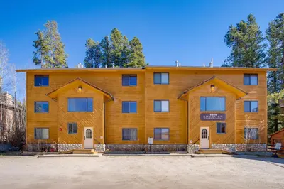 a large wooden building with trees in the background at Steps to Grand Lake New Deck at The Innlet Condo in Grand Lake