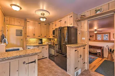 a kitchen with wooden cabinets and stainless steel appliances at Forest-View Creekside Cabins with 4 Acres! in Evergreen