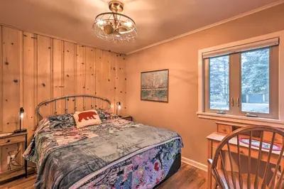 a bedroom with a bed and a window and a chandelier at Forest-View Creekside Cabins with 4 Acres! in Evergreen