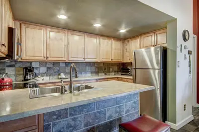 a kitchen with wooden cabinets and a stainless steel refrigerator at Condo on Shuttle Rt-Wild Irishman with Pool and More in Keystone