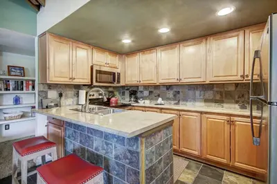 a kitchen with wooden cabinets and a counter top at Condo on Shuttle Rt-Wild Irishman with Pool and More in Keystone