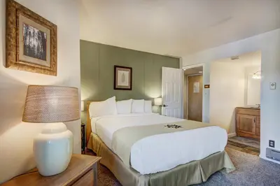 a bedroom with a large bed and a table with a lamp at Condo on Shuttle Rt-Wild Irishman with Pool and More in Keystone