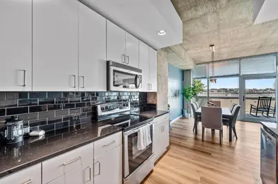 a kitchen with white cabinets and a dining room with a table at 1700 Bassett, Unit 818 in Denver