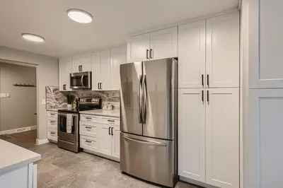 a kitchen with white cabinets and a stainless steel refrigerator at 6636 Depew St (upper) in Arvada