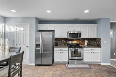a kitchen with white cabinets and a stainless steel refrigerator at 1130 Mockingbird St in Brighton