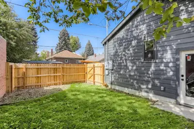 a backyard with a wooden fence next to a house at 2375 Ivanhoe St - Entire House in Denver