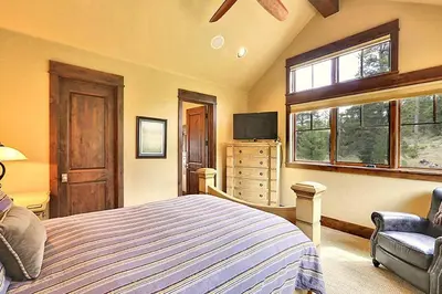 a bedroom with a bed and a tv and windows at Rocky Fells Lodge in Breckenridge