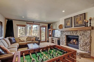 a living room with a pool table in front of a fireplace at Moose Crossing Lodge in Breckenridge