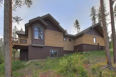 a large wooden house with a balcony on a hill at Moose Crossing Lodge in Breckenridge