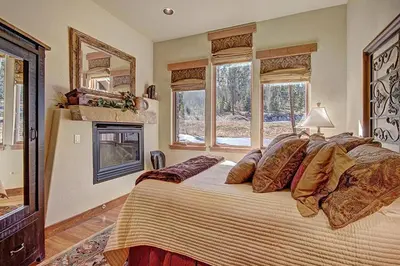 a bedroom with a bed with a fireplace and windows at Moose Crossing Lodge in Breckenridge