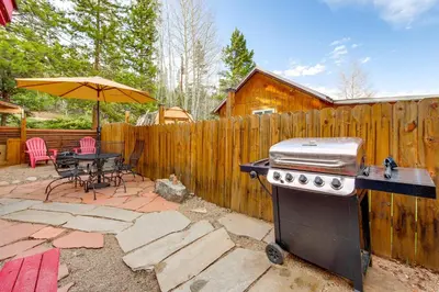 a backyard with a grill and a table and an umbrella at 1 Mi to Grand Lake Pet-Friendly Cabin with Grill! in Grand Lake