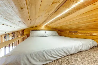 a bed in a room with a wooden ceiling at 1 Mi to Grand Lake Pet-Friendly Cabin with Grill! in Grand Lake