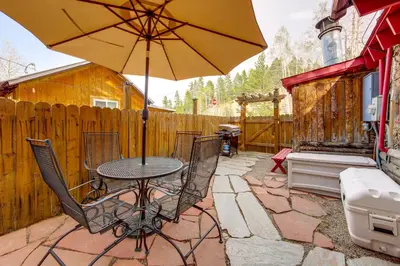 a patio with a table and chairs and an umbrella at 1 Mi to Grand Lake Pet-Friendly Cabin with Grill! in Grand Lake