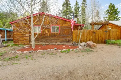 a log cabin with a flag in front of it at 1 Mi to Grand Lake Pet-Friendly Cabin with Grill! in Grand Lake