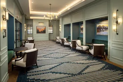 a waiting room with chairs and tables and a rug at The Benson Hotel & Faculty Club in Aurora
