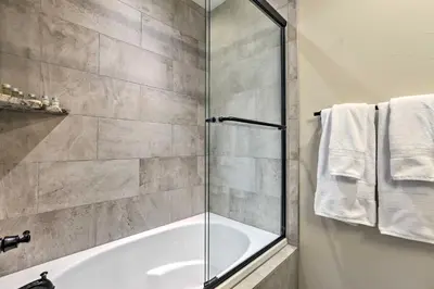 a bathroom with a tub and a glass shower door at half Mi to Dtwn Golden Gem with Patios! in Golden