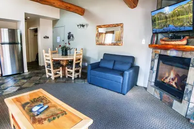 a living room with a fireplace and a blue chair at King Bed Condo with Personal Hot Tub on Deck with River View condo in Estes Park