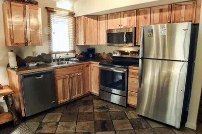 a kitchen with wooden cabinets and stainless steel appliances at King Bed Condo with Personal Hot Tub on Deck with River View condo in Estes Park