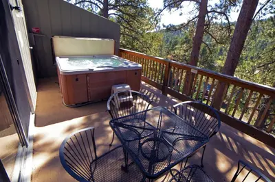 a patio with chairs and a grill on a deck at King Bed Condo with Personal Hot Tub on Deck with River View condo in Estes Park