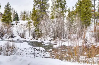 a stream in a snow covered forest with trees at Spacious Frisco Retreat with Private Hot Tub! in Frisco
