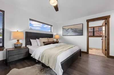 a bedroom with a large bed and two windows at Rocky Mountain Gem! Two Large patios, Fireplace and Private Jacuzzi in Estes Park