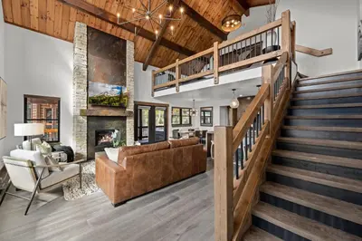 a living room with a staircase and a couch and a fireplace at Rocky Mountain Gem! Two Large patios, Fireplace and Private Jacuzzi in Estes Park