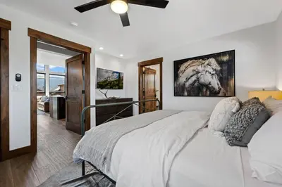 a bedroom with a large bed with a ceiling fan at Estes Dream! Brand New End Unit with Two Patios, Indoor/Outdoor Fireplace and Jacuzzi in Estes Park