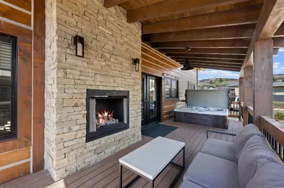an outdoor living room with a fireplace and a tv at Estes Dream! Brand New End Unit with Two Patios, Indoor/Outdoor Fireplace and Jacuzzi in Estes Park