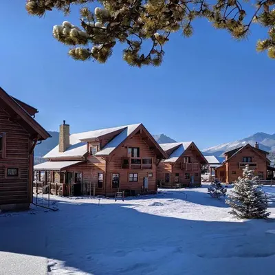 a group of wooden buildings in the snow at Estes Dream! Brand New End Unit with Two Patios, Indoor/Outdoor Fireplace and Jacuzzi in Estes Park