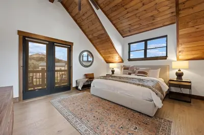 a bedroom with a large bed and a wooden ceiling at Estes Dream! Brand New End Unit with Two Patios, Indoor/Outdoor Fireplace and Jacuzzi in Estes Park