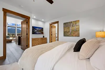 a white bedroom with a large bed and a sliding glass door at Elk Haven! Two Large Patios, Private Jacuzzi, Indoor/Outdoor Fireplace in Estes Park