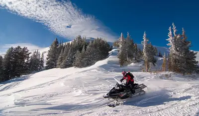 a person riding a snowmobile down a snow covered slope at Elk Haven! Two Large Patios, Private Jacuzzi, Indoor/Outdoor Fireplace in Estes Park