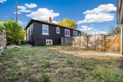 a black house with a fence in front of it at Peaceful Home w/ 4BR, Big Yard and amazing art in Denver