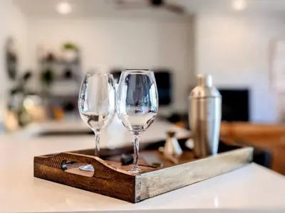 two wine glasses sitting on a wooden tray on a counter at HostWise Stays - The River West - Hot Tub, Parking, Fire Pit, and more in Silverthorne
