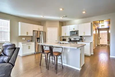 a kitchen with white cabinets and bar stools at 10 Mi to DIA Spacious Aurora House with Yard! in Aurora