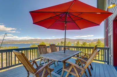 a wooden table with chairs and an umbrella on a deck at Granby Home Stunning Mountain and Lake Views! in Granby