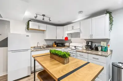 a kitchen with white cabinets and a wooden table at Basement with Full Kitchen and Near Downtown in Denver