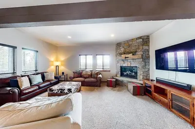 a living room with a large television and a stone fireplace at Tabernash Tranquility in Tabernash