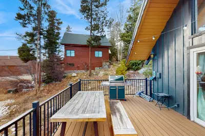 a wooden deck with a bench and a grill on a house at The Golden Moose Chalet in Grand Lake