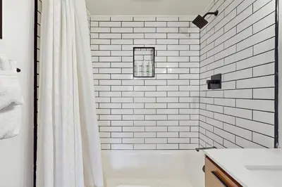 a white tiled bathroom with a shower and a sink at The Golden Moose Chalet in Grand Lake