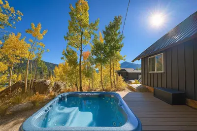 a hot tub on a deck next to a house at The Golden Moose Chalet in Grand Lake