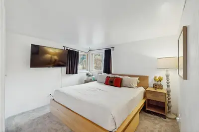 a white bedroom with a bed and a window at The Golden Moose Chalet in Grand Lake
