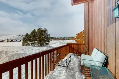 a snow covered balcony with two chairs on a building at Grand Lake Lookout in Grand Lake