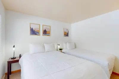 two beds in a bedroom with white walls at Grand Lake Lookout in Grand Lake