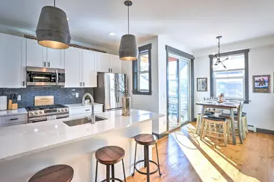 a kitchen with white cabinets and a counter with stools at Modern Mountain Getaway, Walk to Grand Lake! in Grand Lake