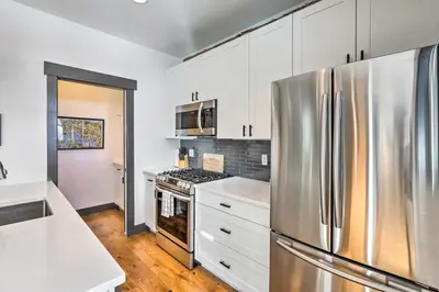 a kitchen with white cabinets and a stainless steel refrigerator at Modern Mountain Getaway, Walk to Grand Lake! in Grand Lake
