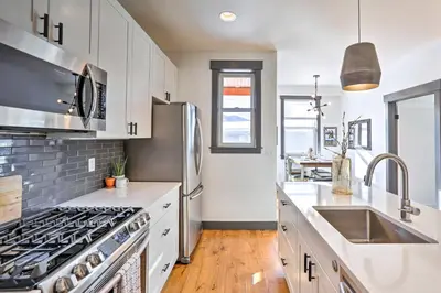 a kitchen with white cabinets and a stainless steel refrigerator at Modern Mountain Getaway, Walk to Grand Lake! in Grand Lake